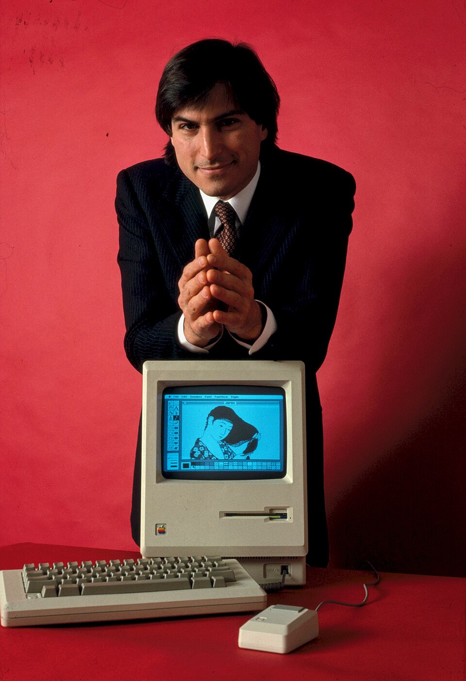 Steve Jobs standing behind a Macintosh computer in January 1984
