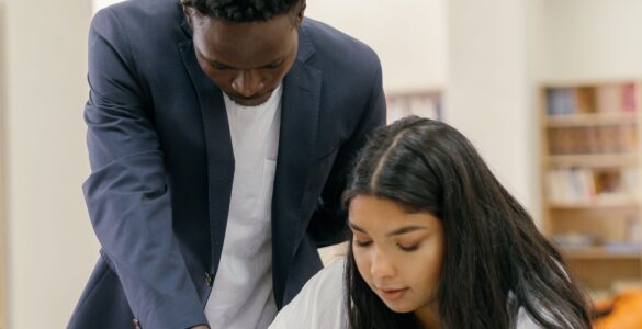A college student and advisor reviewing course questions at a desk before professor office hours
