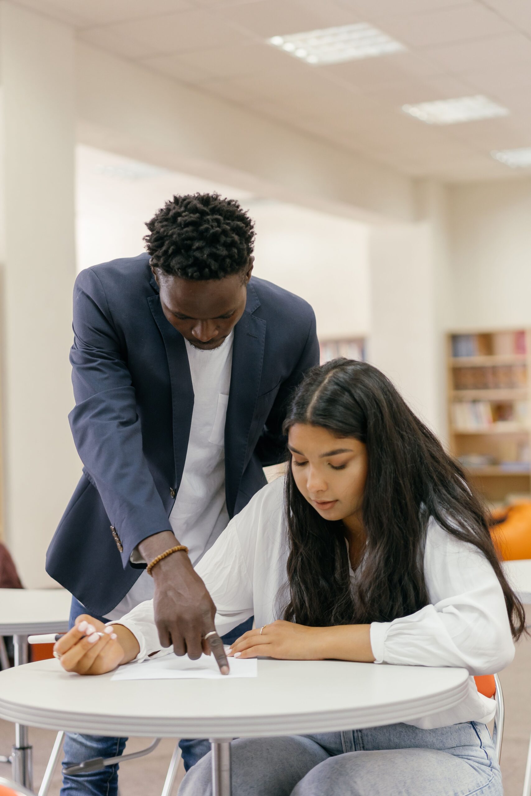 An advisor points to paperwork while a student reviews a course plan.