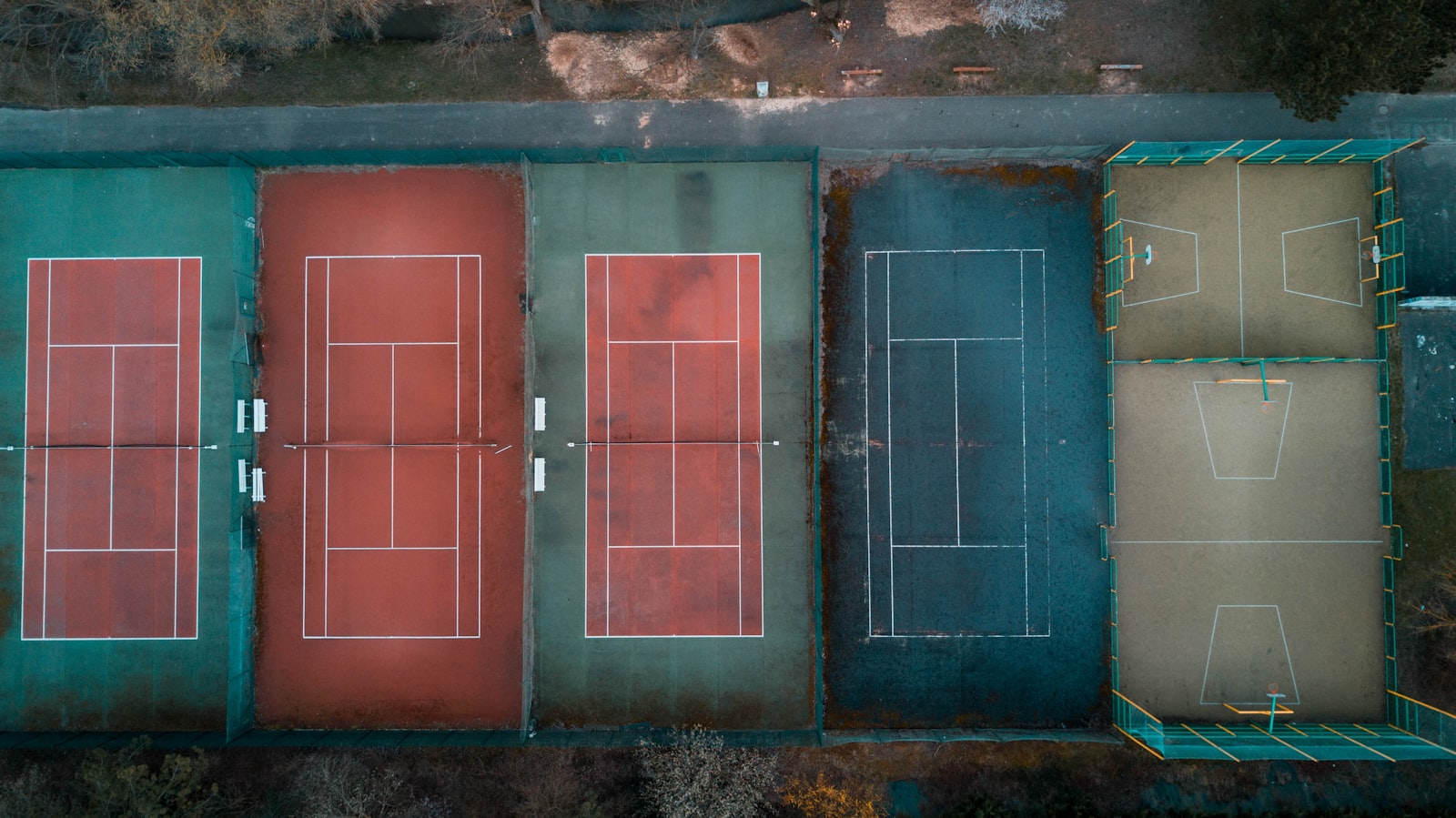 An aerial view of several tennis courts with different colored surfaces