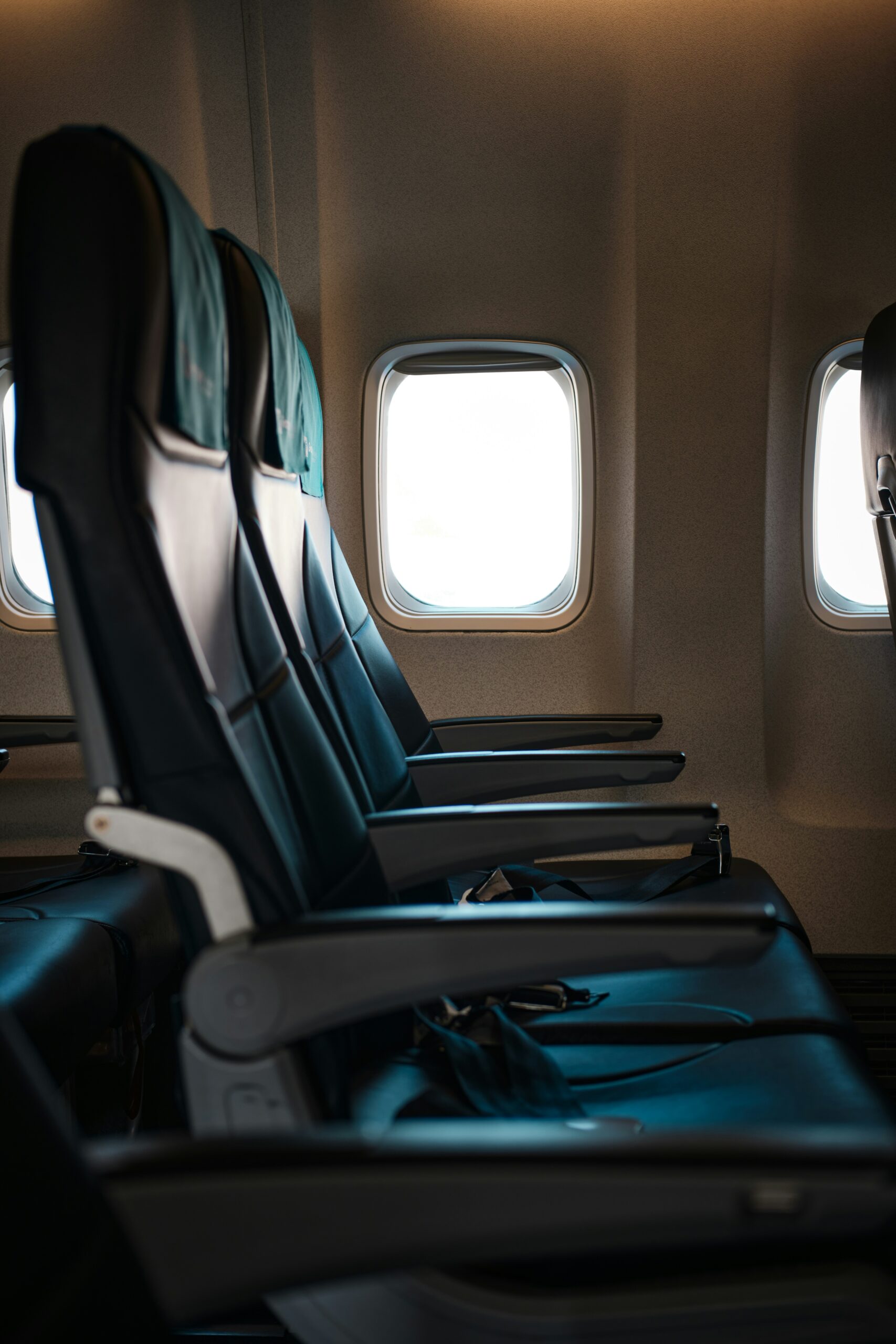 Empty airplane seats with seat belts visible near the windows