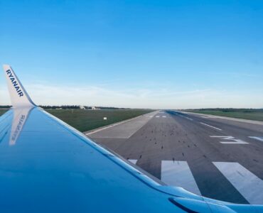 View from an airplane window showing a wing and runway before a flight involving cabin pressure changes