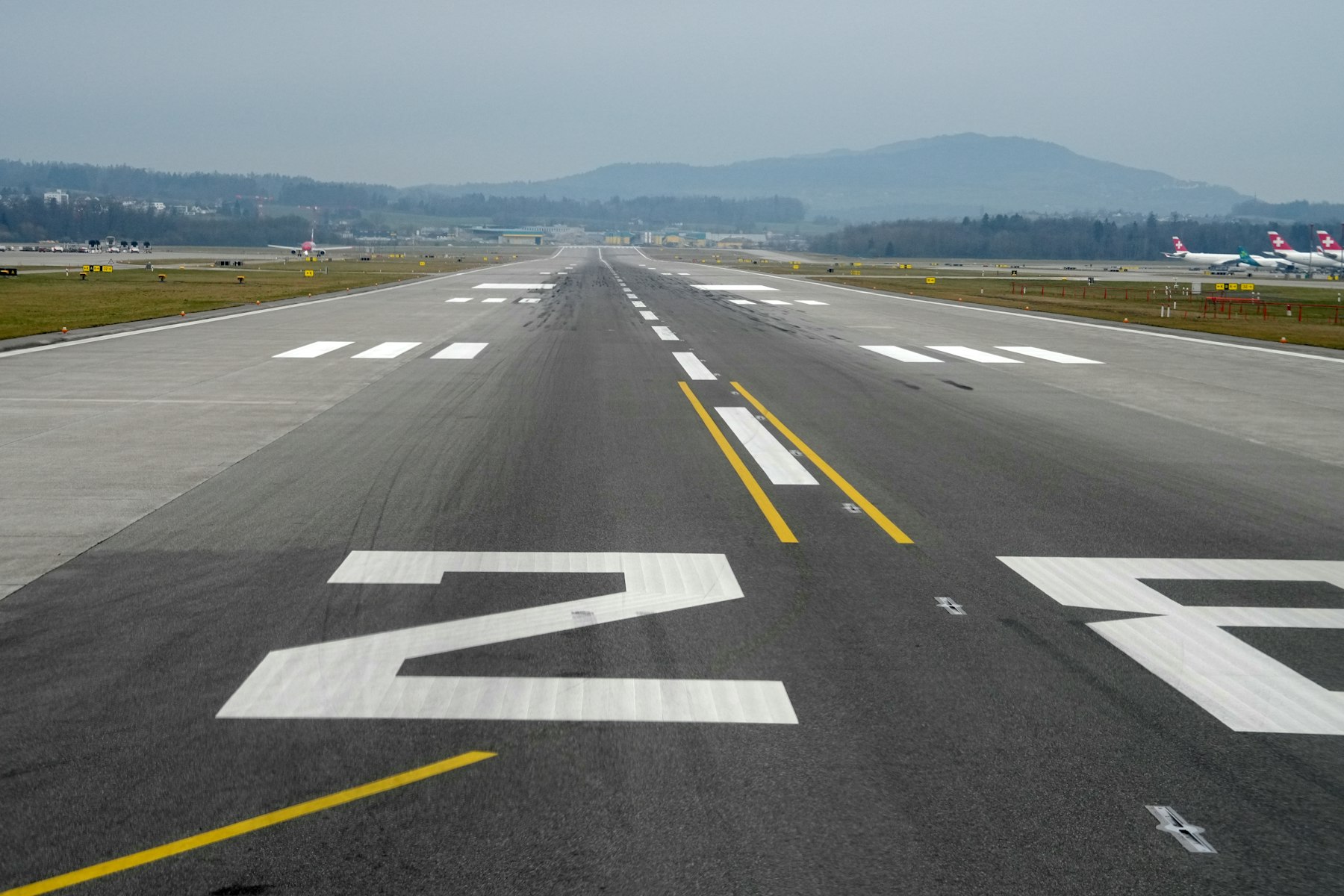 White runway markings and numbers painted on a wide airport runway