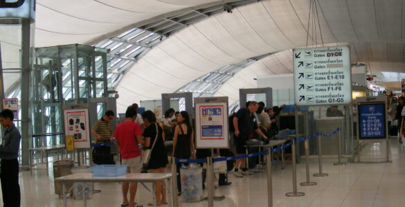 Passengers placing bags on an airport security X-ray conveyor