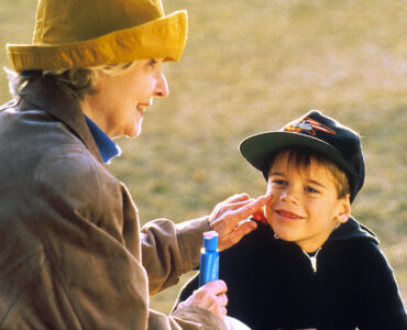 An adult applying sunscreen to a child outdoors