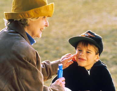 An adult applying sunscreen to a child outdoors