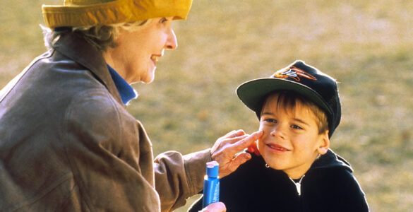 An adult applying sunscreen to a child outdoors