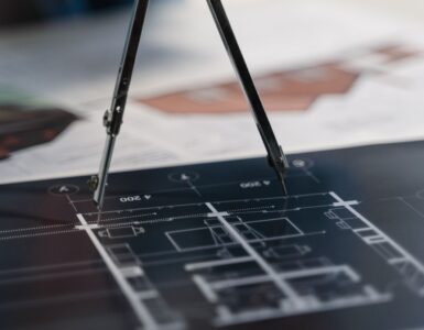 A drawing compass set over an architectural scale drawing