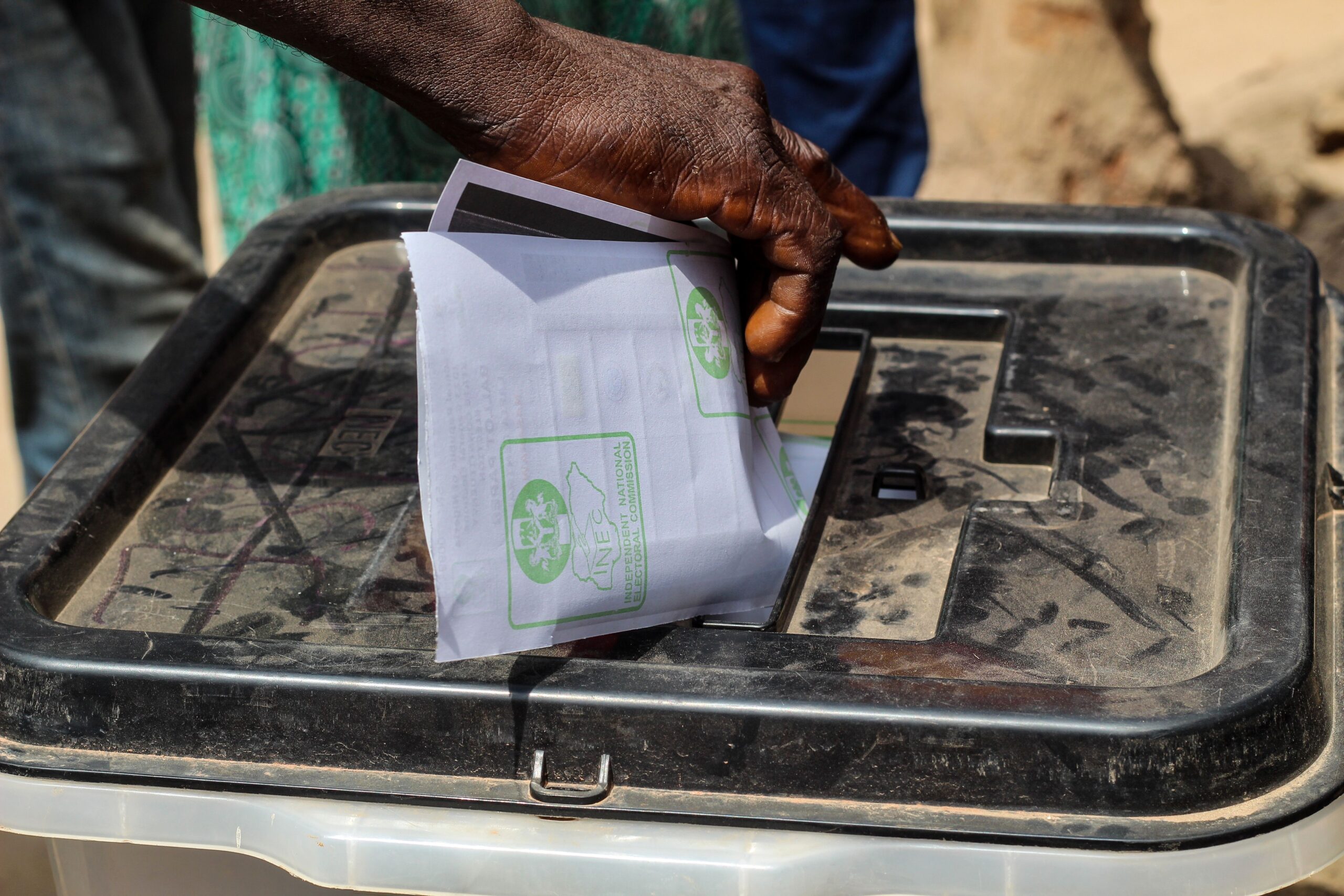 A voter places a paper ballot into a ballot box