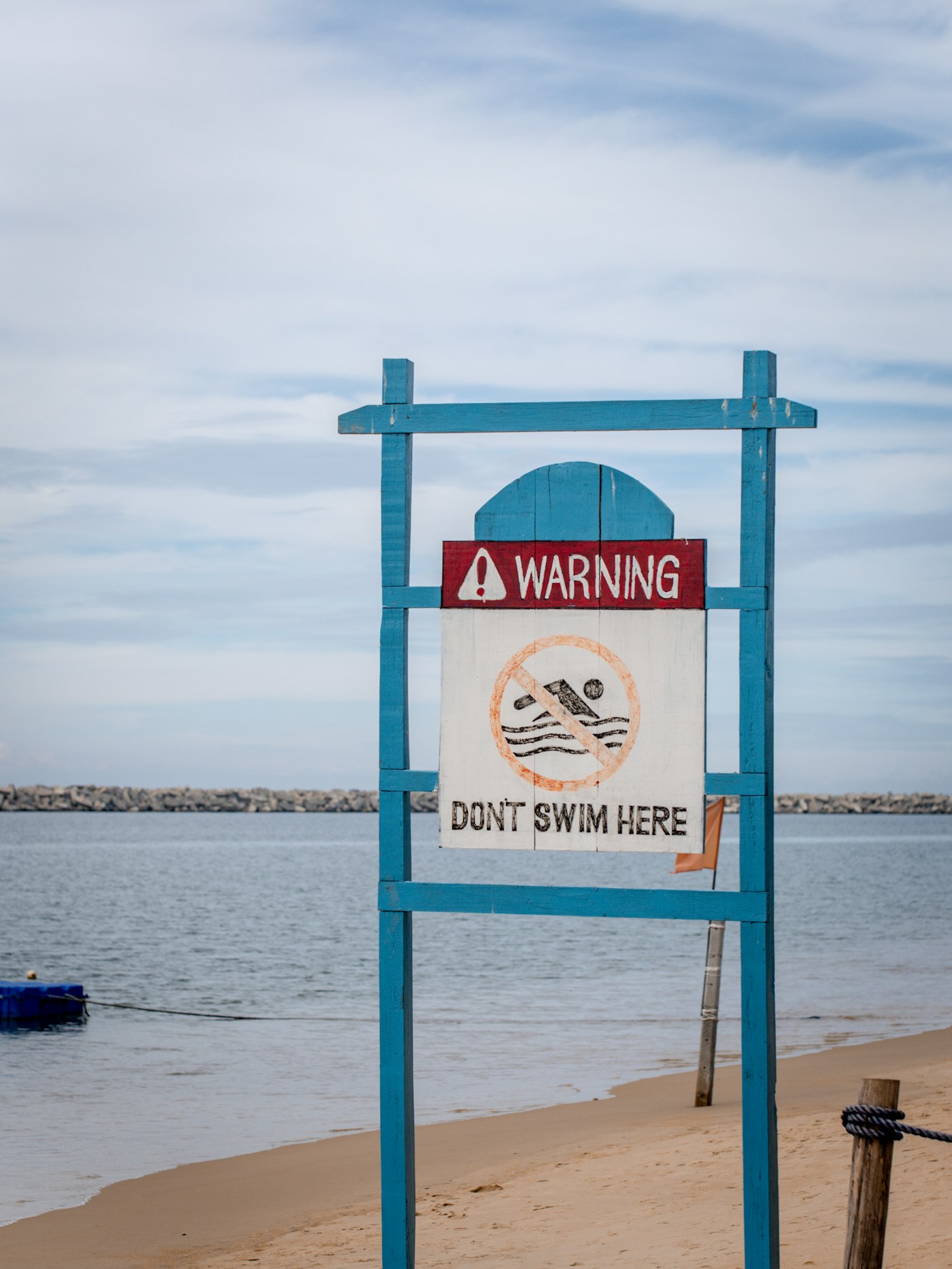 A warning sign on a beach telling swimmers not to enter the water.