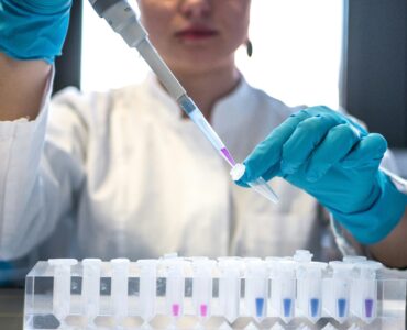 A chemist using a pipette to add liquid to small test tubes