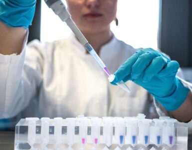 A chemist using a pipette to add liquid to small test tubes