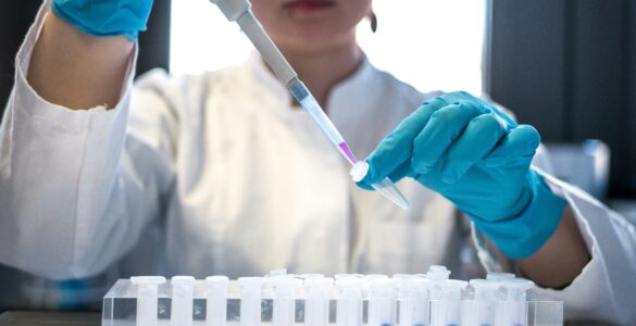 A chemist using a pipette to add liquid to small test tubes