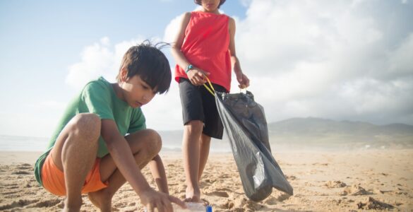 Children picking up a plastic bottle during a beach cleanup
