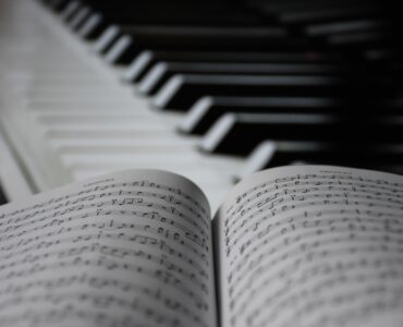 Open sheet music resting near piano keys