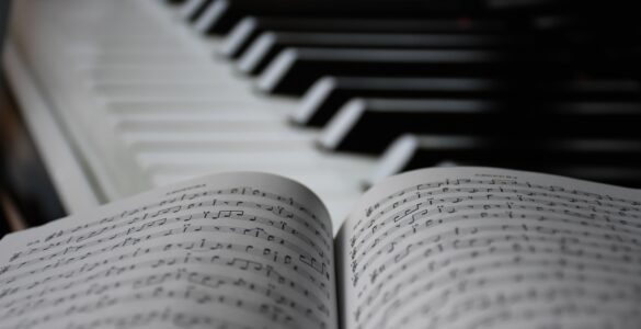 Open sheet music beside piano keys for studying harmonic arrivals and cadences.