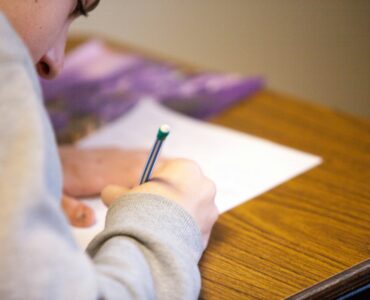 A student writes during a college credit-by-exam test for possible prior learning credit