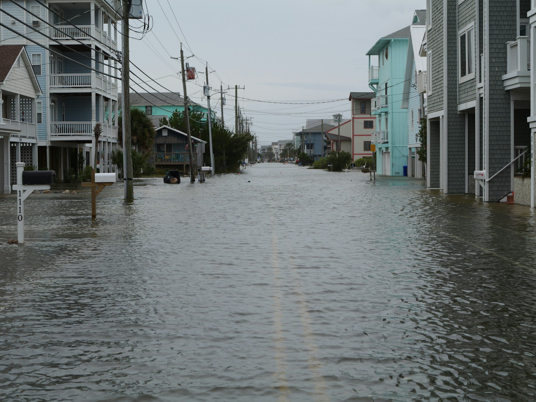 Floodwater covering a coastal street between raised beach houses