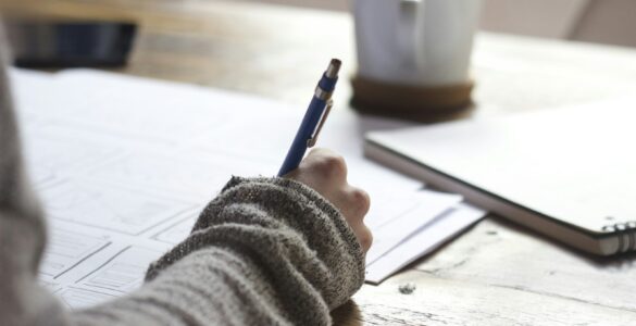 A student writing notes while preparing a college waitlist response