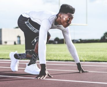 A track athlete crouches at a starting line, representing college sports eligibility planning