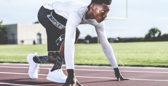 A track athlete crouches at a starting line, representing college sports eligibility planning