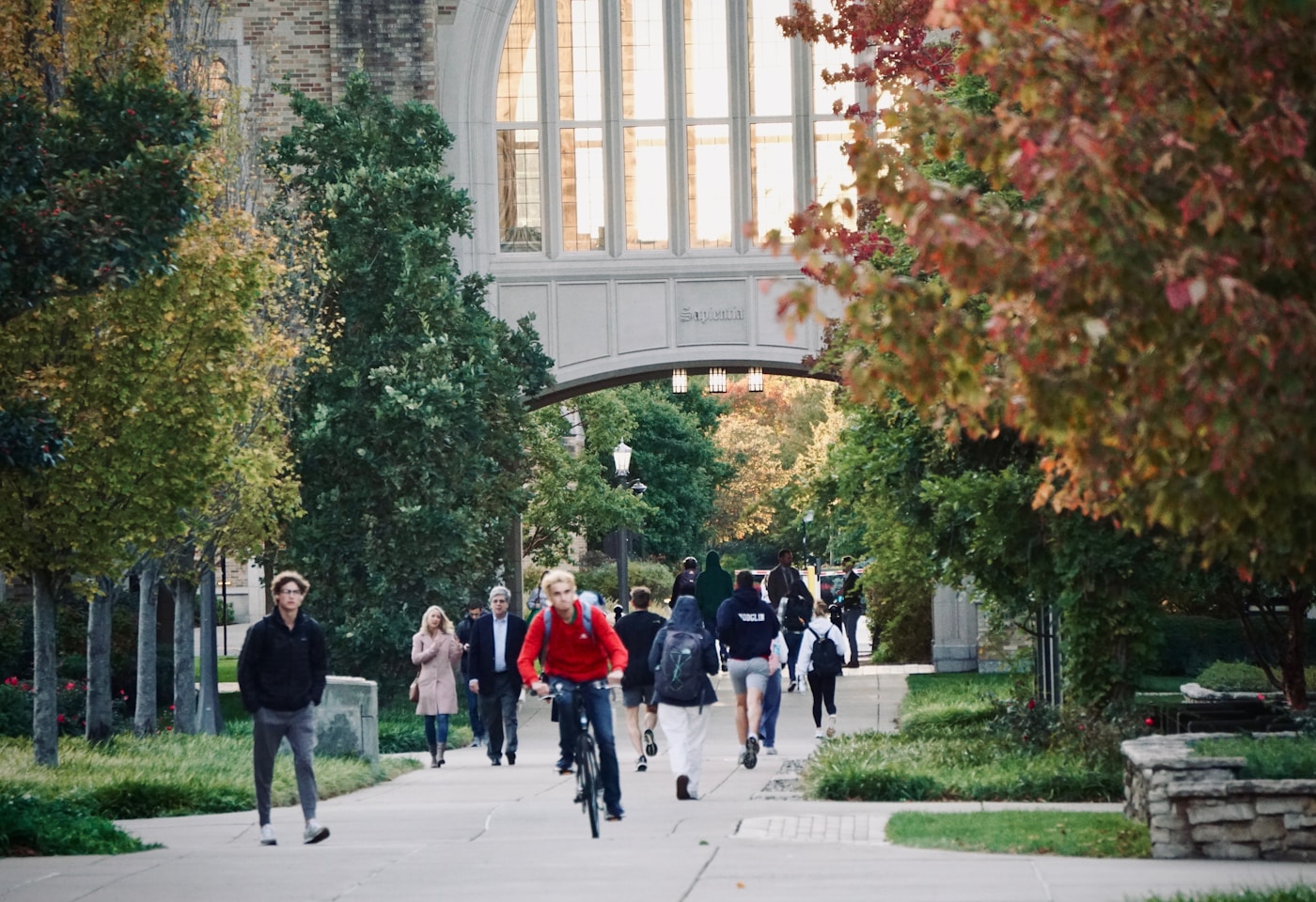 Students walk across a college campus path between classes.