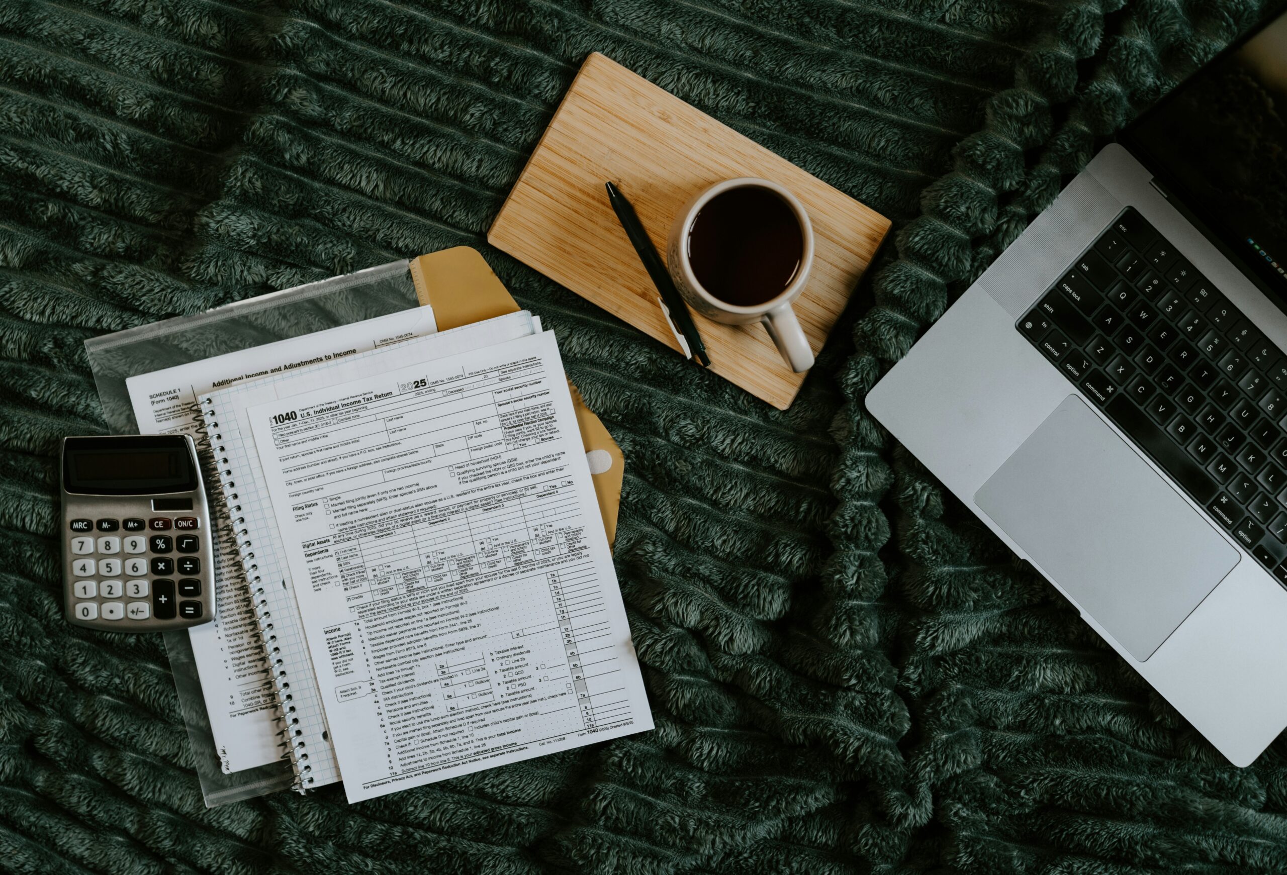 A laptop, calculator, and financial paperwork laid out for budgeting.