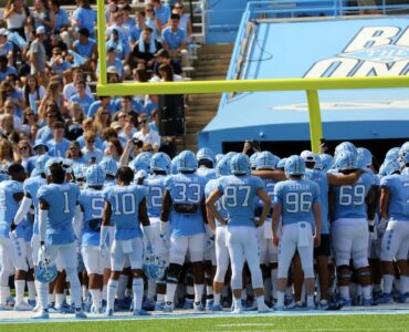 College football players gather on a stadium field before a game