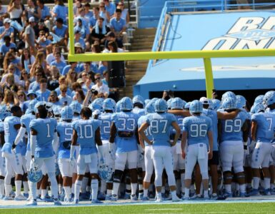 College football players gather on a stadium field before a game