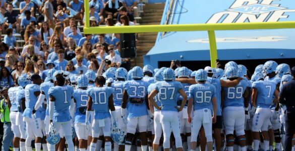 College football players gather on a stadium field before a game