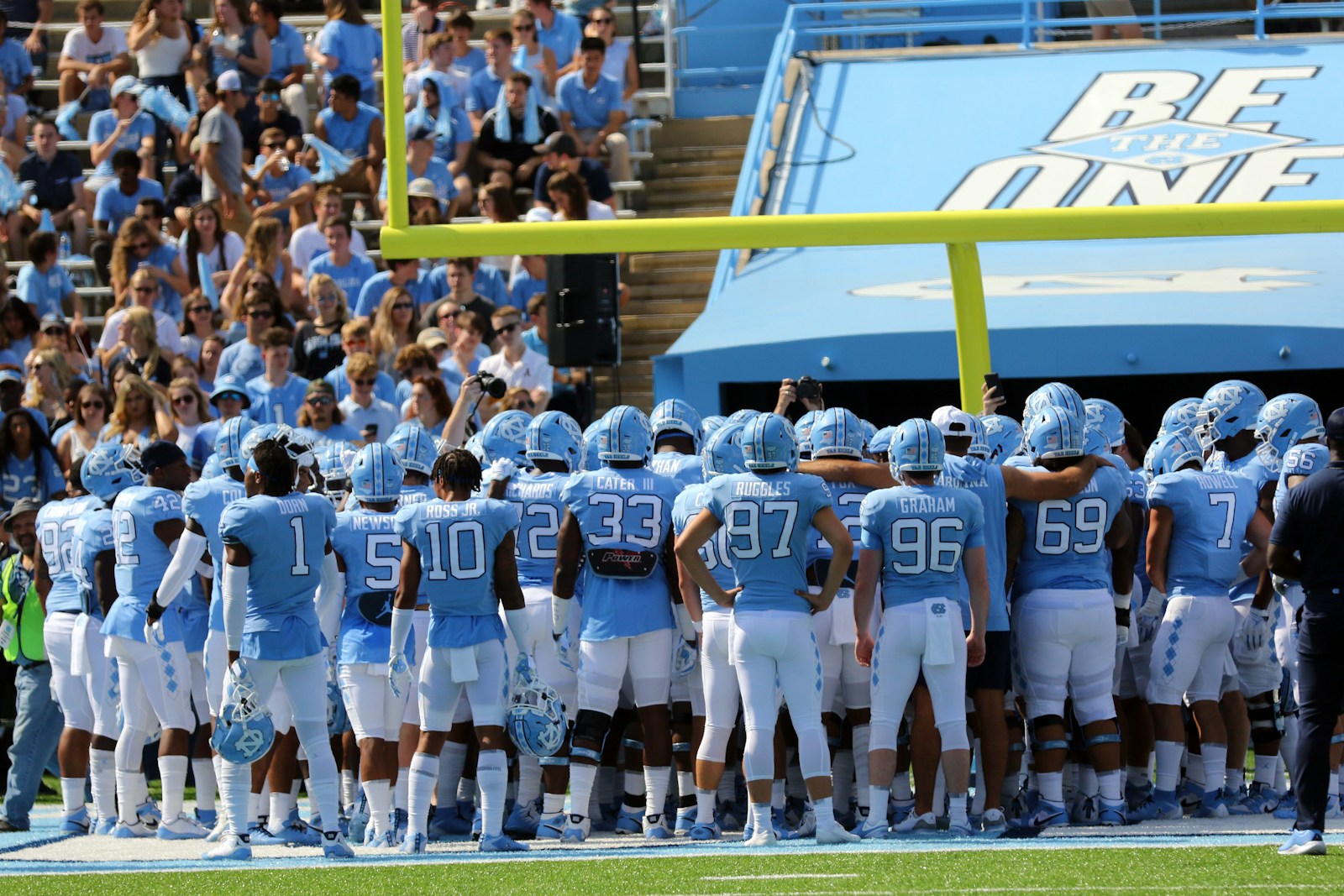 College football players gather on a stadium field before a game