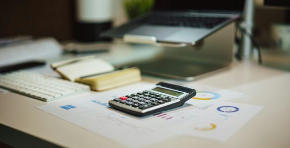 A calculator on financial planning papers beside a laptop.