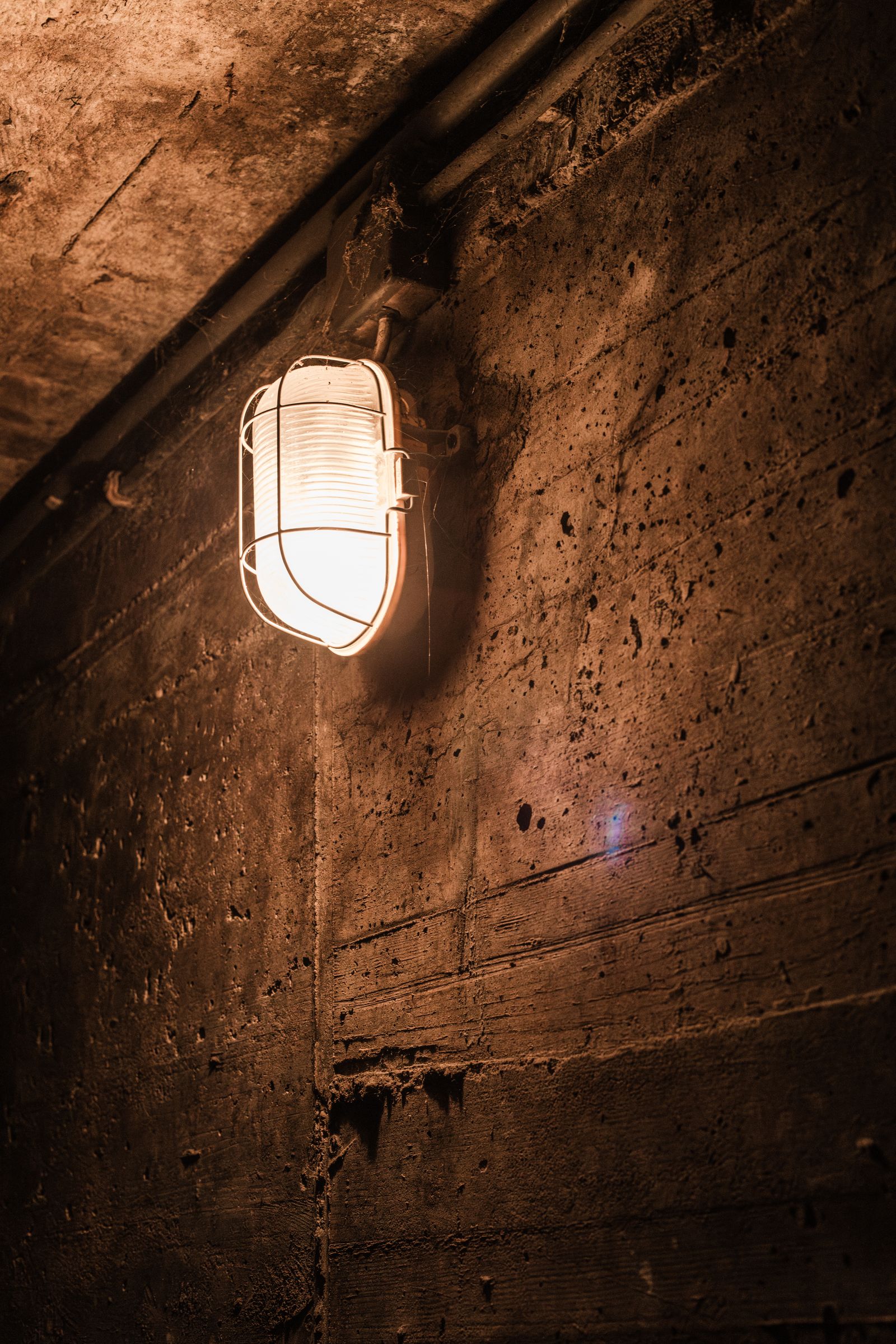 A concrete basement wall lit by a wall lamp