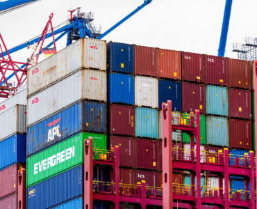 A container ship loaded with cargo at a port terminal for an explanation of imports, exports, and trade deficits.
