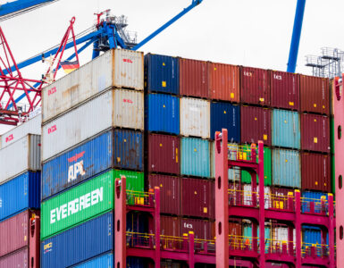 A container ship loaded with cargo at a port terminal for an explanation of imports, exports, and trade deficits.