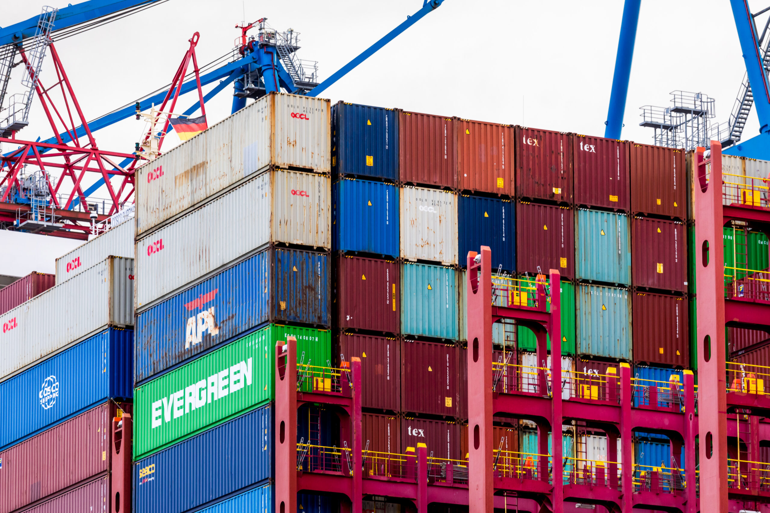 A container ship loaded with cargo at a port terminal for an explanation of imports, exports, and trade deficits.