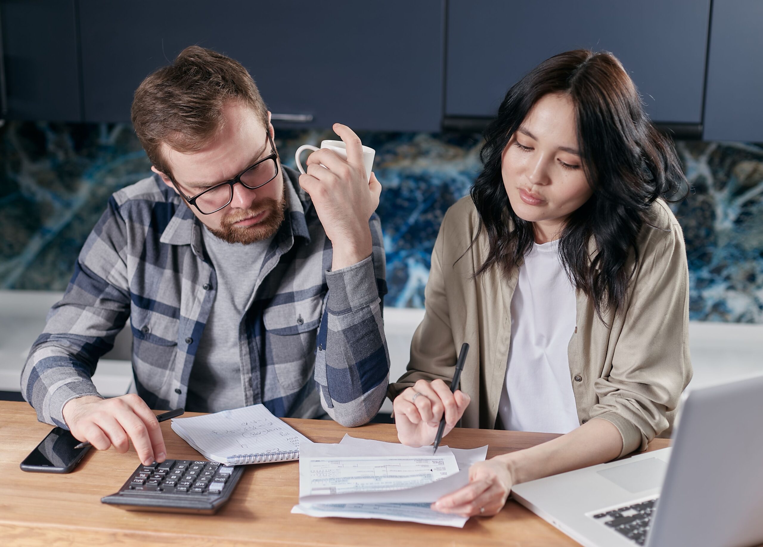 Two people reviewing bills and choices with a calculator and laptop