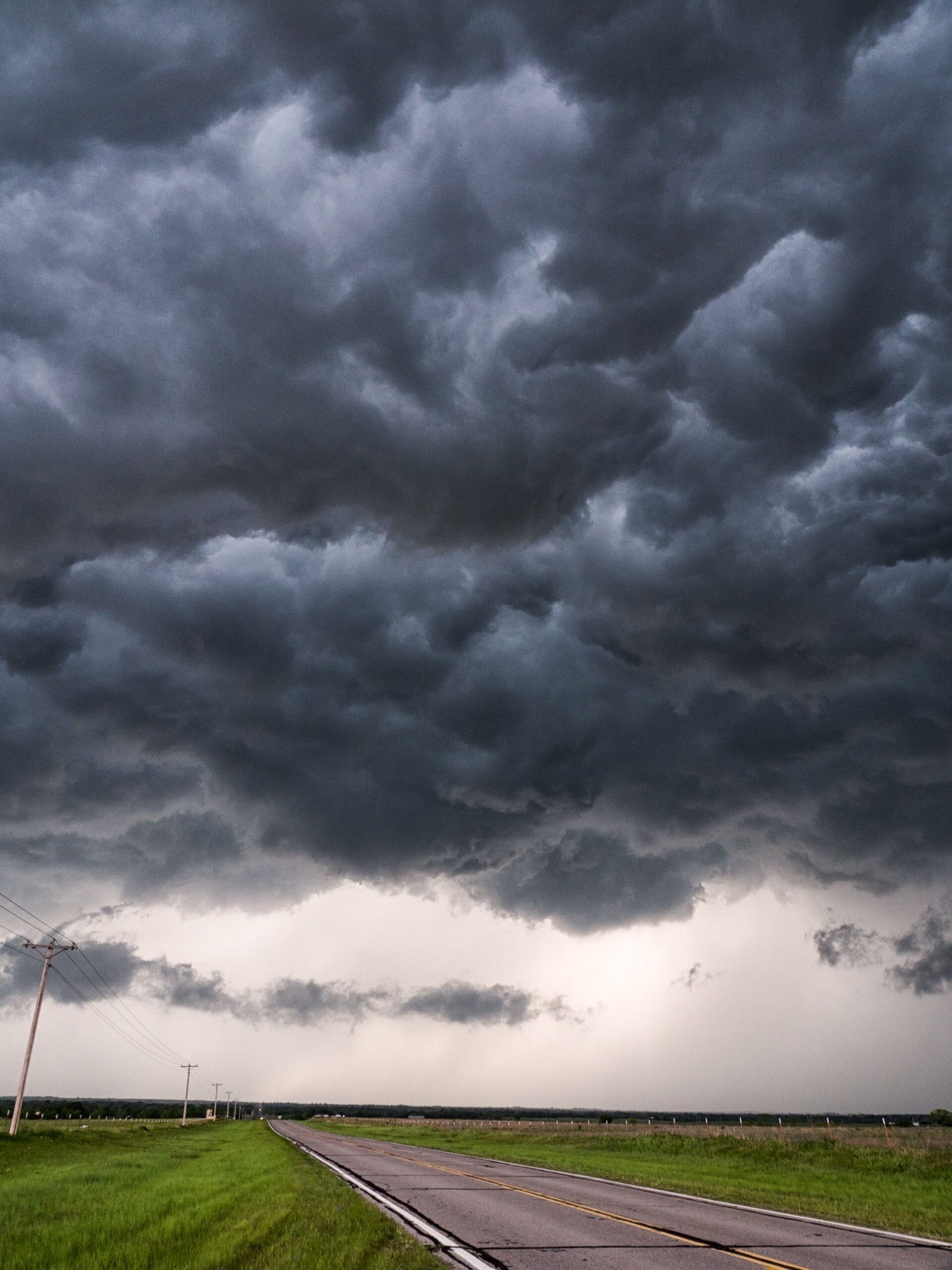Dark storm clouds approaching over a quiet countryside road.