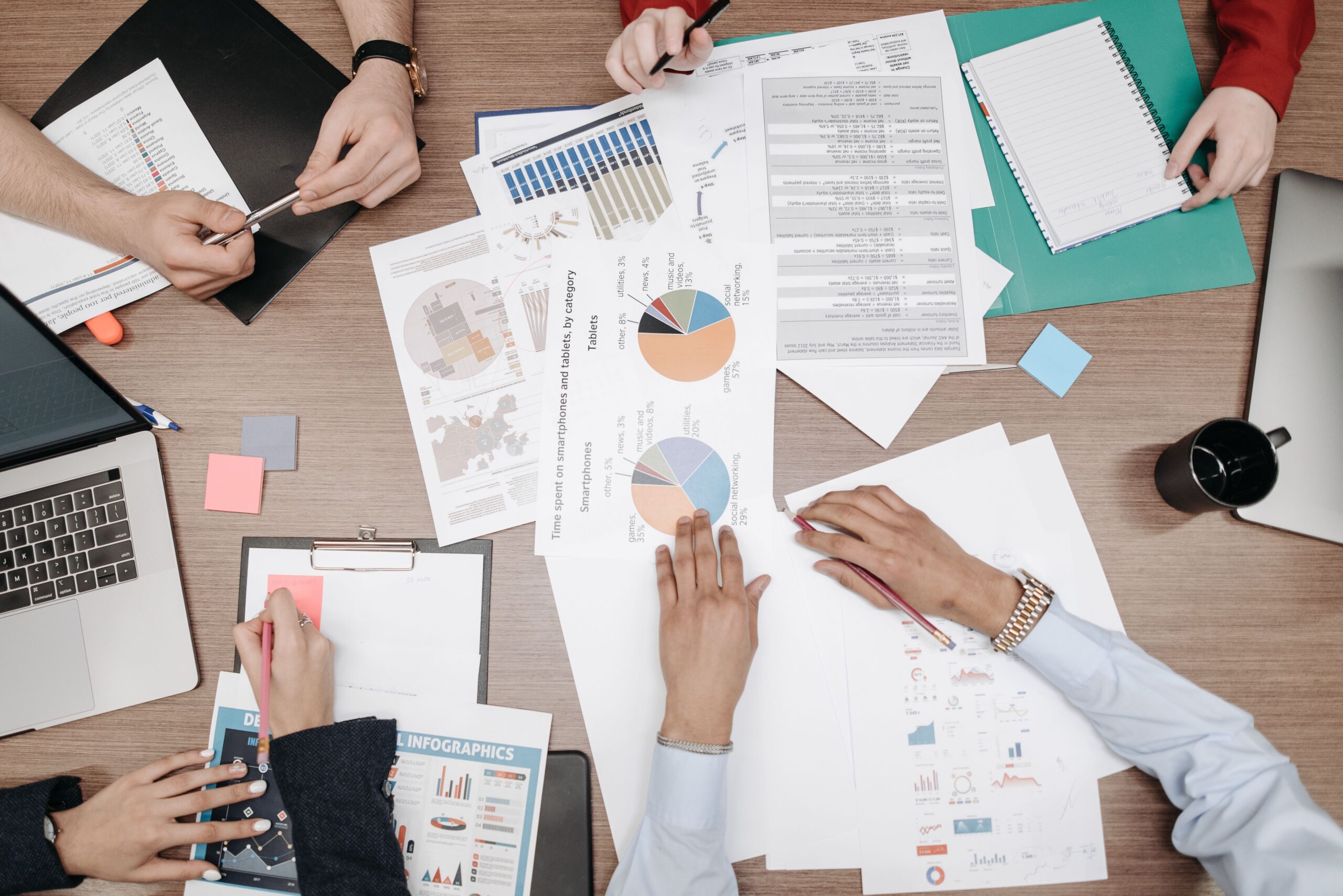 Several people reviewing printed charts and data reports on a table