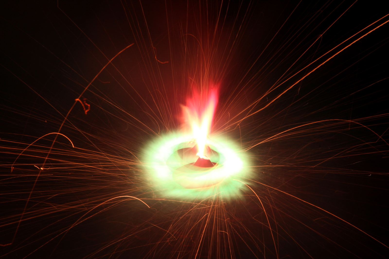 A spinning firework glowing red and green with bright sparks