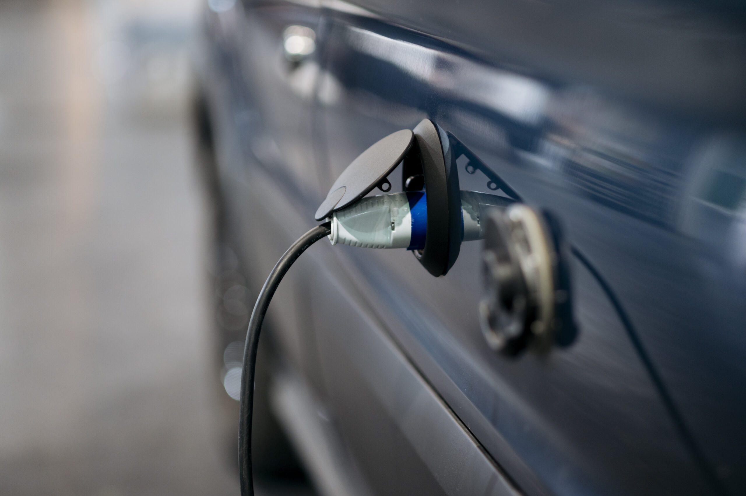 An electric car plugged into a charging station during the day