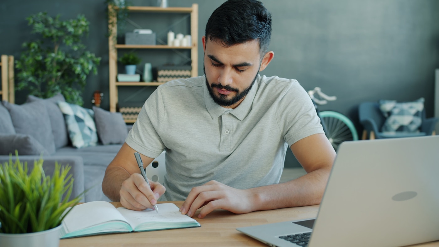 A notebook and laptop on a desk during an essay drafting session.