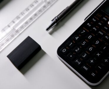 A calculator, pen, ruler, and eraser on a desk for working through probability calculations.
