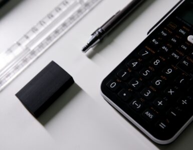 A calculator, pen, ruler, and eraser on a desk for working through probability calculations.