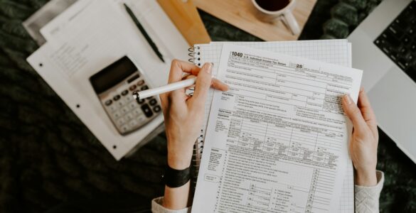 Financial forms, a notebook, and a calculator arranged beside a laptop.