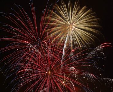 Red, gold, and white fireworks bursting against a dark night sky