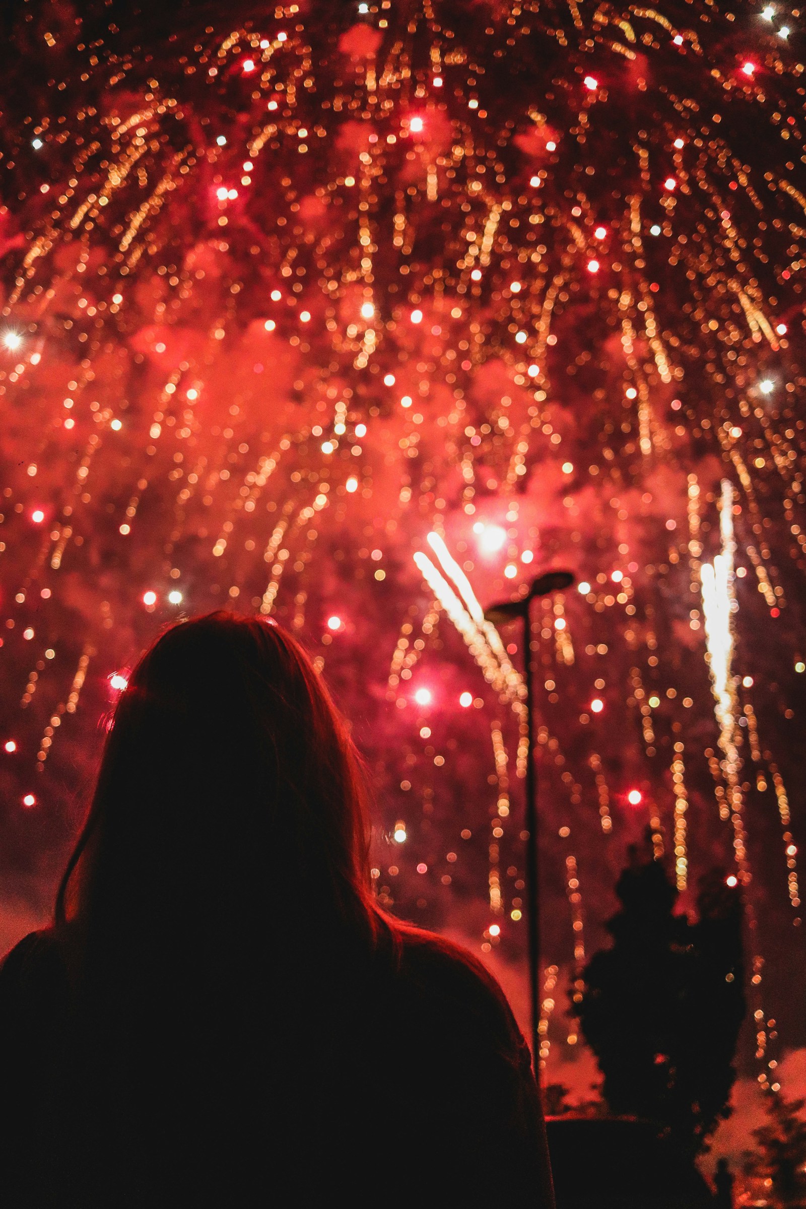 A crowd watches fireworks as smoke gathers in the night sky