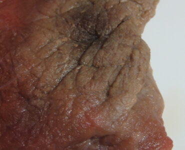 Freezer burn causing dry, discolored patches on a piece of frozen beef
