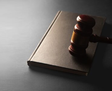 A wooden gavel resting on a closed law book for a civics discussion