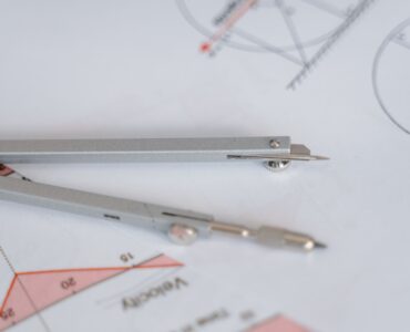 A compass and ruler resting on a geometry diagram for studying scale factors and dilations.